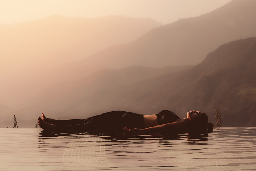 Morning light with Beautiful Attractive Asian woman practice yoga Dead Body or Savasana on the pool above the Mountain peak in front of beautiful nature views in SAPA vietnam,so comfortable,Warm Tone