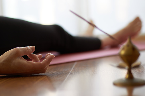 woman practicing yoga, lying in yoga nidra pose, exercise in Shavasana, exercises, work, rest after practice, female hand. Healthy lifestyle concept